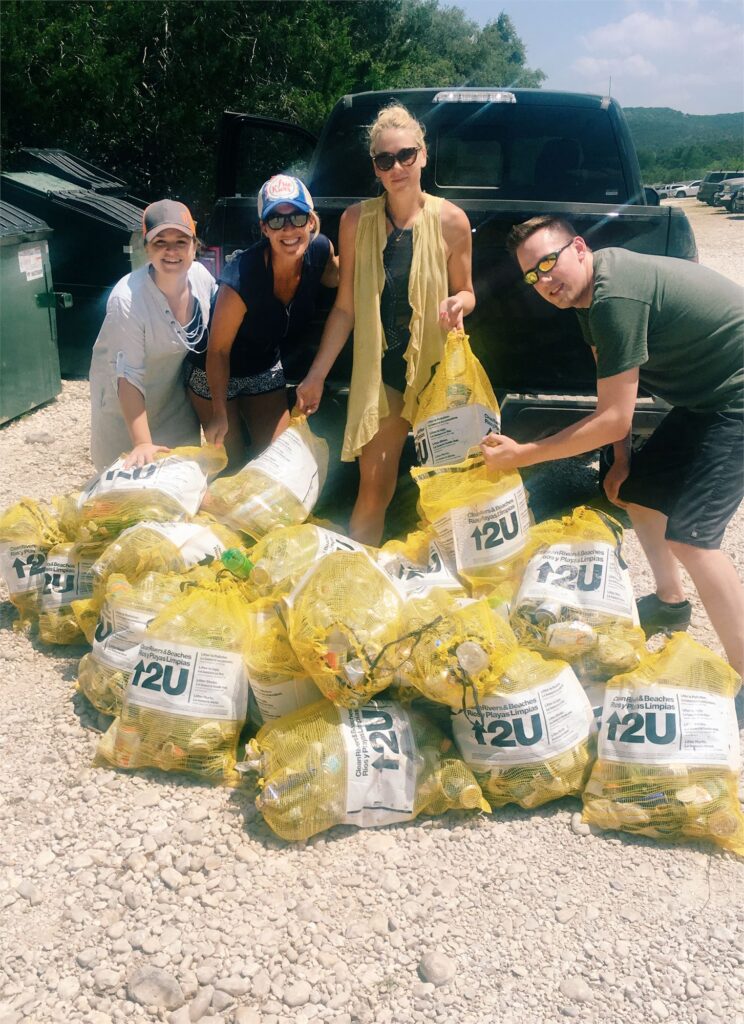 group of people with filled river trash bags