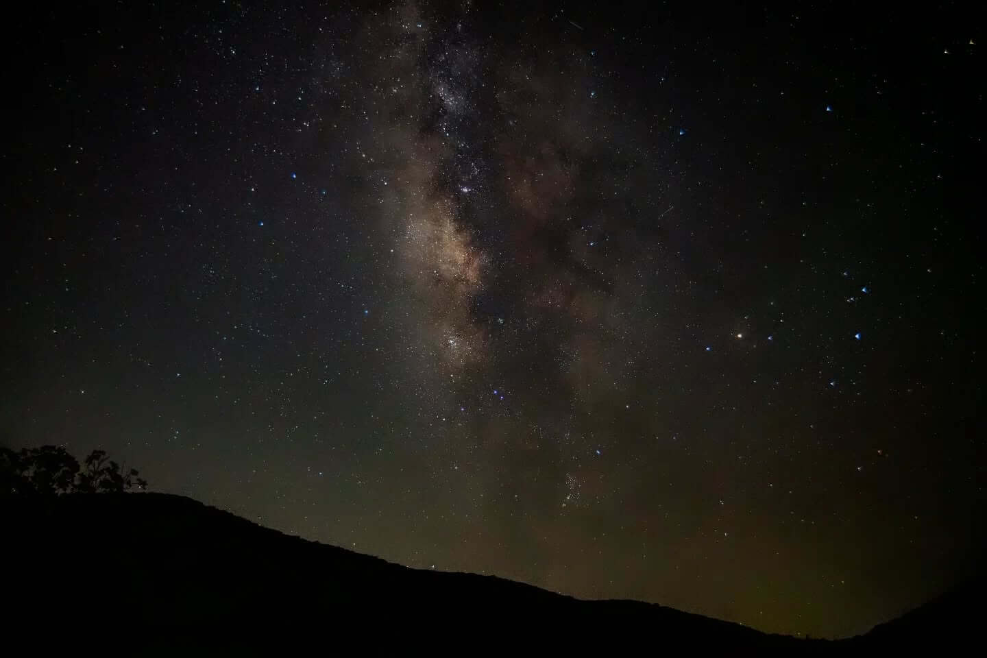 A breathtaking night sky filled with countless stars and the glowing Milky Way, silhouetted against the dark hills of Uvalde County, Texas in Uvalde County, Texas