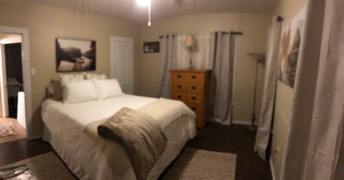 A cozy bedroom with a large bed, wooden dresser, and soft lighting in Uvalde County, Texas