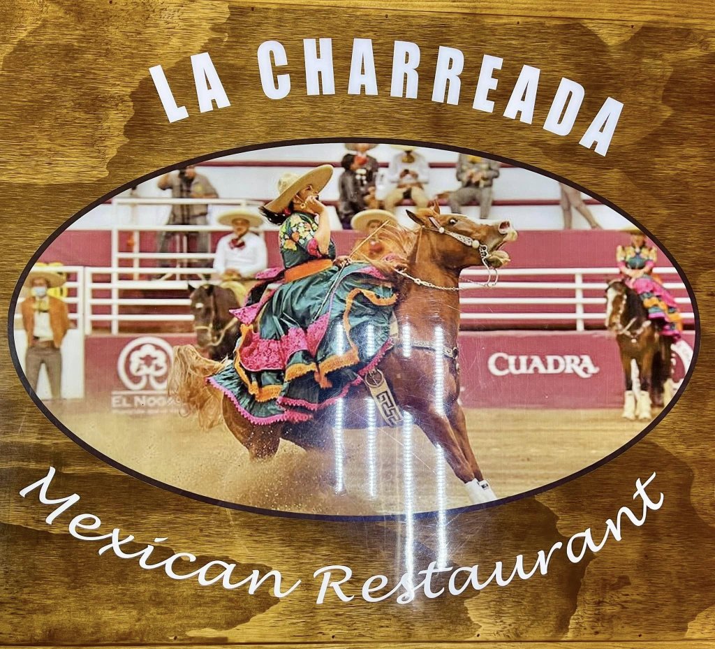 A vibrant scene of a Mexican charreada, showcasing a rider in traditional attire on a galloping horse, surrounded by spectators and other participants in Uvalde County, Texas