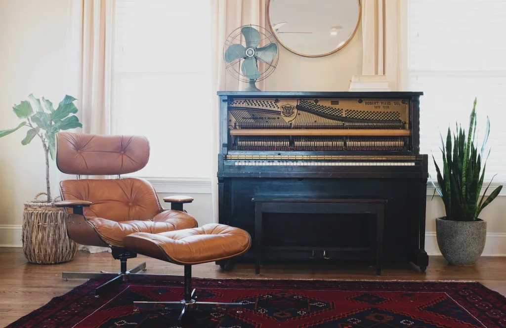 A cozy living room features a vintage upright piano, a modern leather recliner, and a variety of indoor plants in Uvalde County, Texas