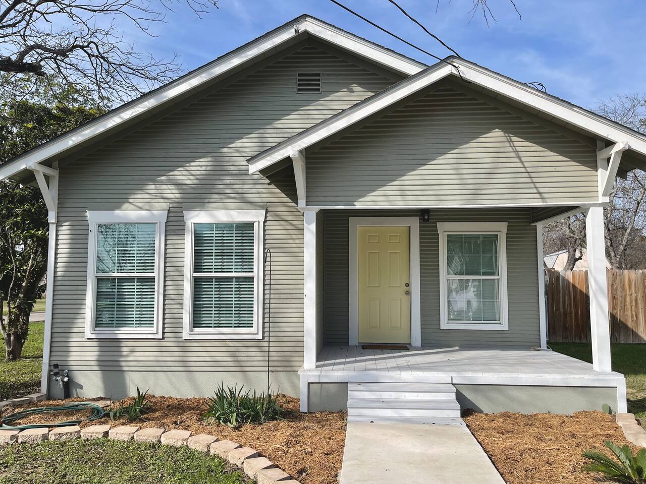 A charming two-bedroom house with a covered front porch, set in a residential neighborhood with a well-maintained lawn and landscaping in Uvalde County, Texas
