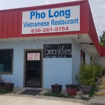A vibrant Vietnamese restaurant with a red awning and blue walls, featuring a smoothie bar and outdoor seating in Uvalde County, Texas