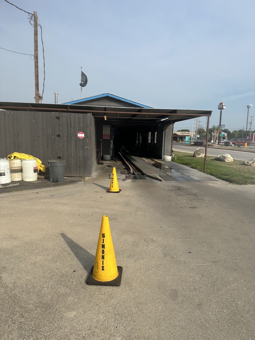 A car wash entrance with yellow safety cones and a dark building with a blue roof in Uvalde County, Texas