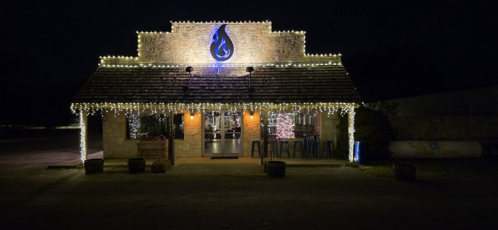 A quaint building in Uvalde County, Texas, is beautifully illuminated with warm white lights, creating a festive atmosphere against the dark night sky in Uvalde County, Texas