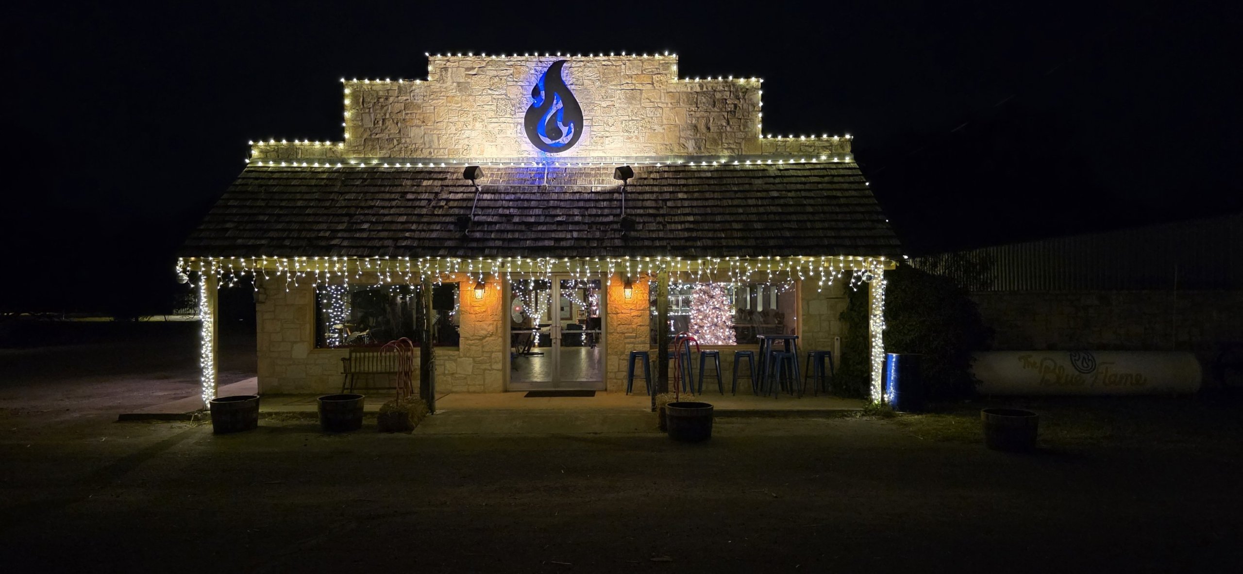 A quaint building in Uvalde County, Texas, is beautifully illuminated with warm white lights, creating a festive atmosphere against the dark night sky in Uvalde County, Texas